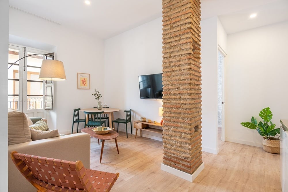 a living room with a brick column and a flat screen tv