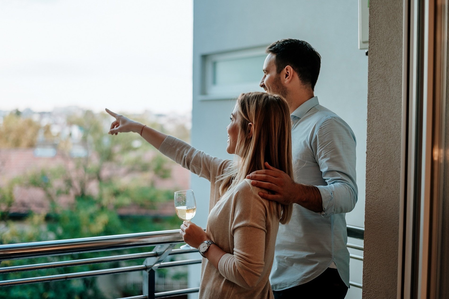 a man and a woman are standing on a balcony and the woman is pointing