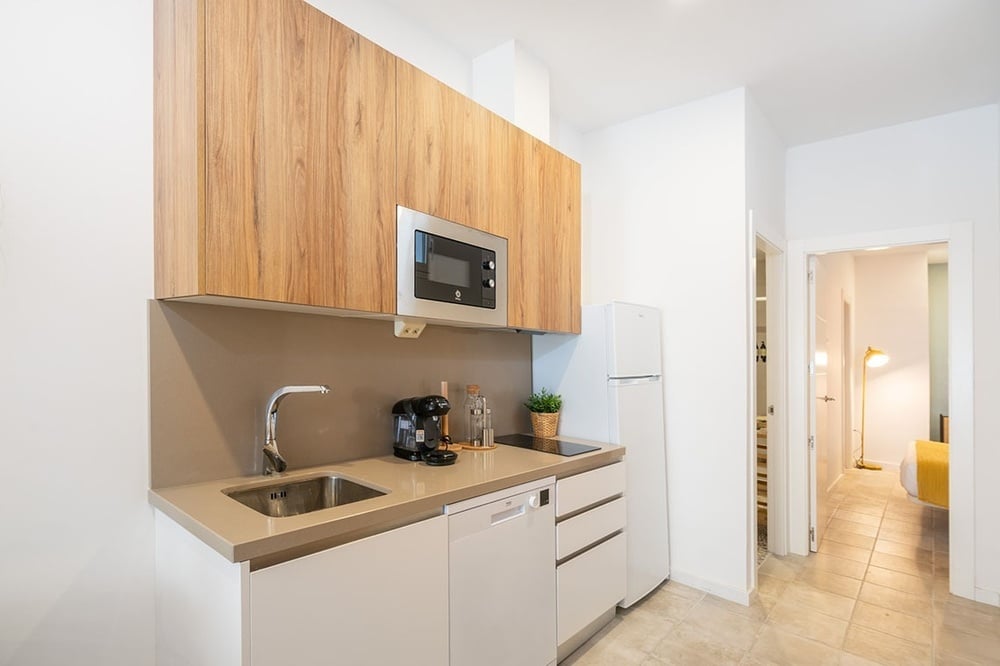 una pequeña cocina con gabinetes de madera y electrodomésticos de acero inoxidable