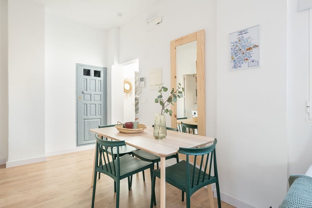 una mesa de comedor con sillas verdes y un mapa en la pared