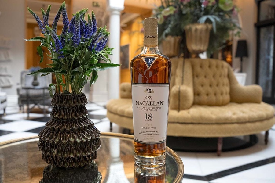 una botella de macallan está sobre una mesa junto a un jarrón de flores