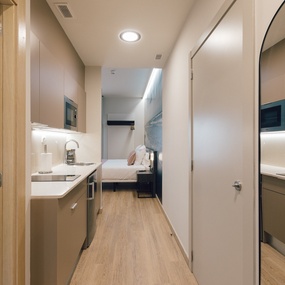 a narrow hallway leading to a bedroom and kitchen