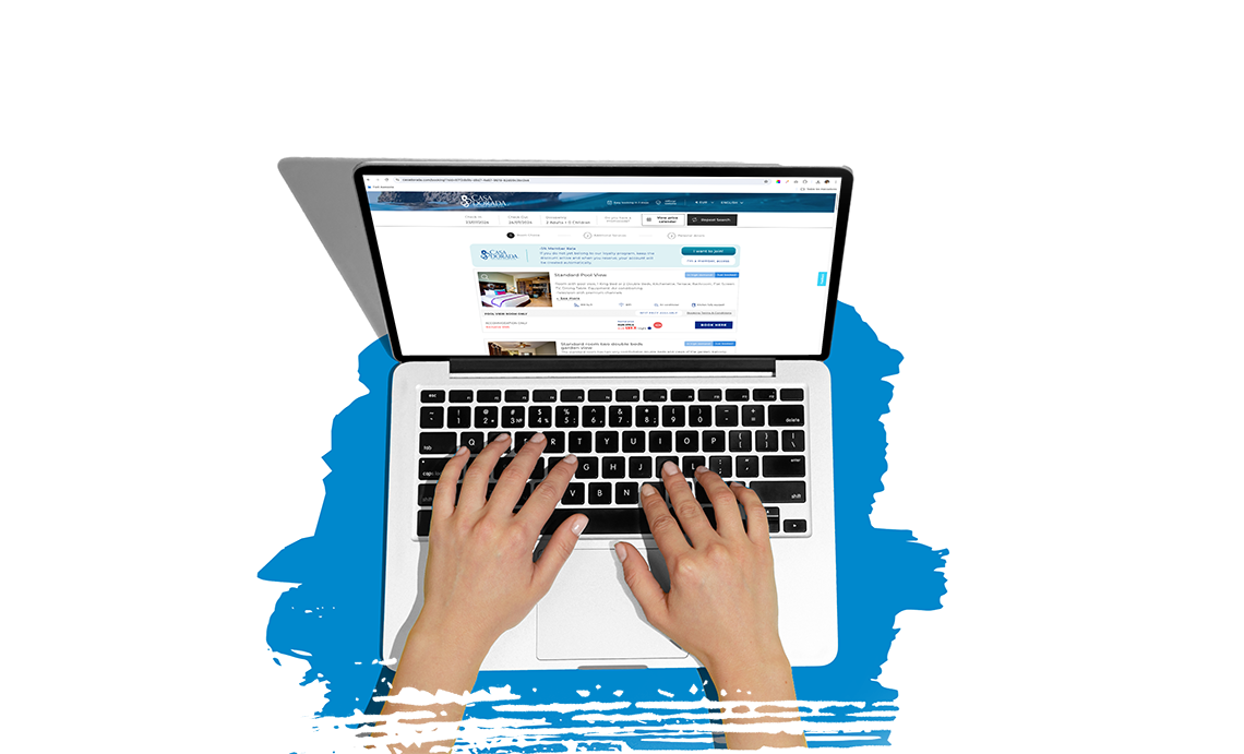 una mujer se sienta en una mesa con una computadora portátil y un teléfono inteligente