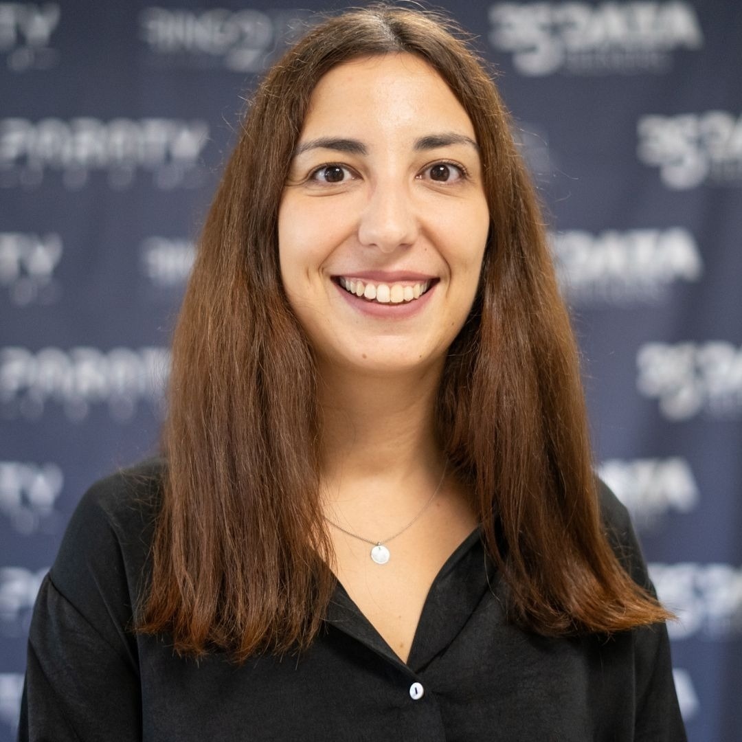 a woman wearing a black shirt and a necklace smiles in front of a sign that says data