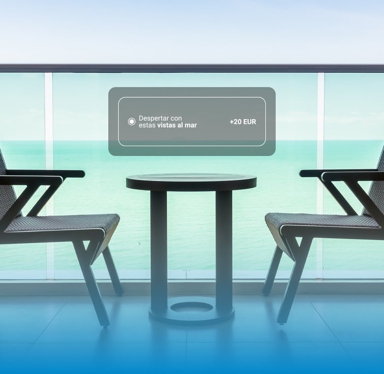 Un balcón con sillas y una mesa ofrece una vista al mar, con una opción de "Despertar con estas Vistas al mar" disponible por +20 EUR.