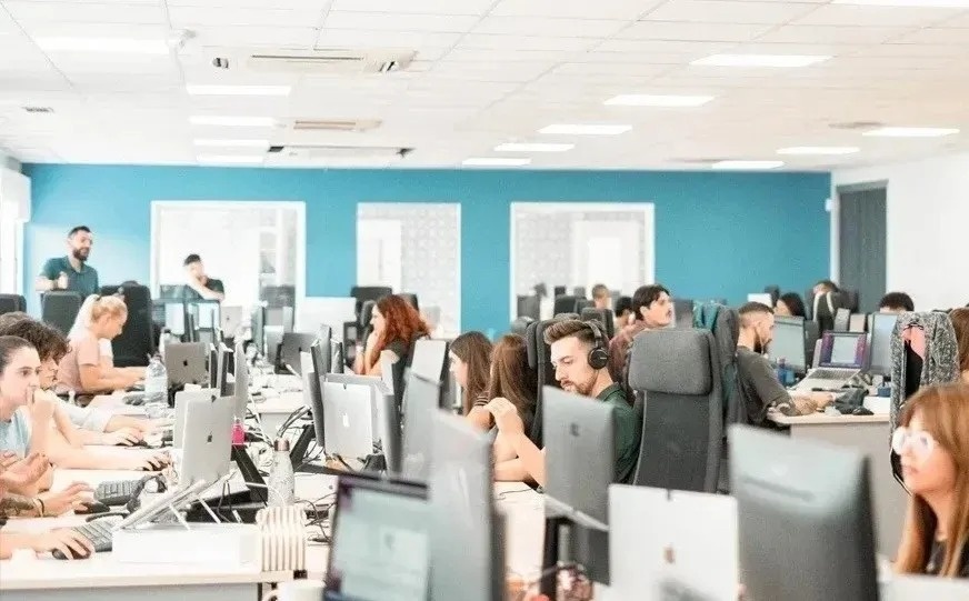 un grupo de personas están sentadas en escritorios con computadoras