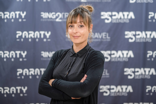 a woman stands in front of a paraty banner