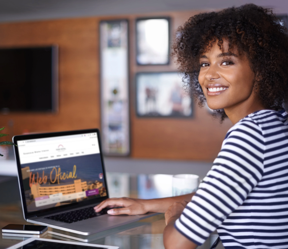 a woman is smiling while using a laptop that says web oficial on the screen
