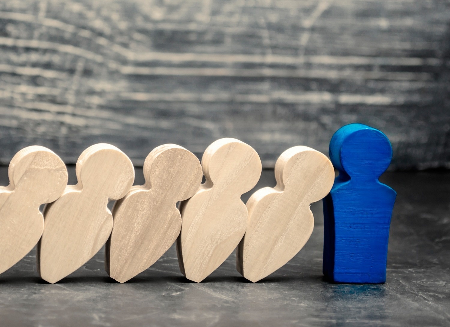 a blue wooden figure stands in front of a row of wooden figures