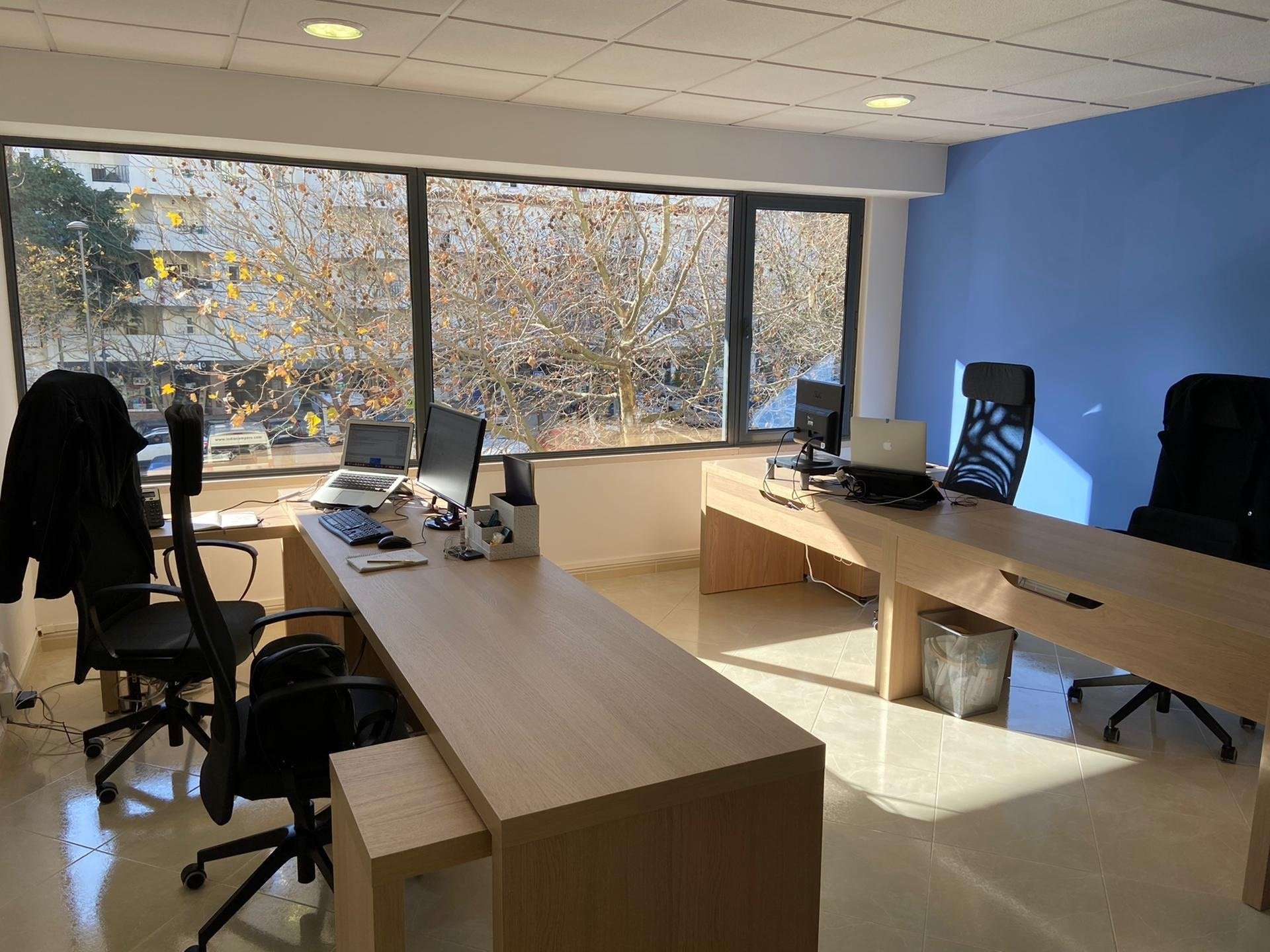 uma sala de escritório com mesas de madeira e cadeiras