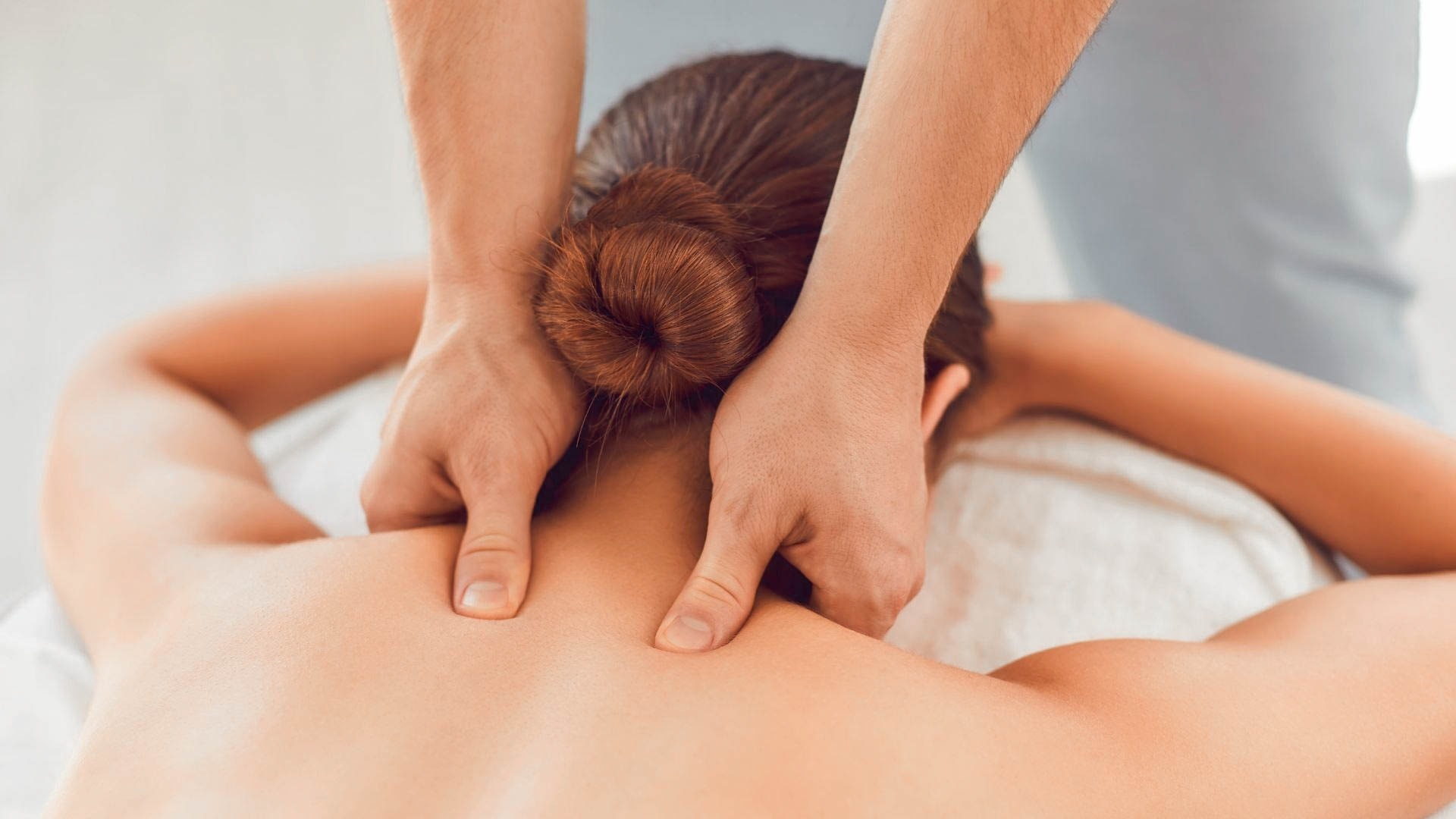 a woman is getting a massage with her hair in a bun