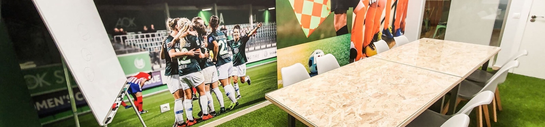 a room with a table and chairs has a picture of soccer players on the wall