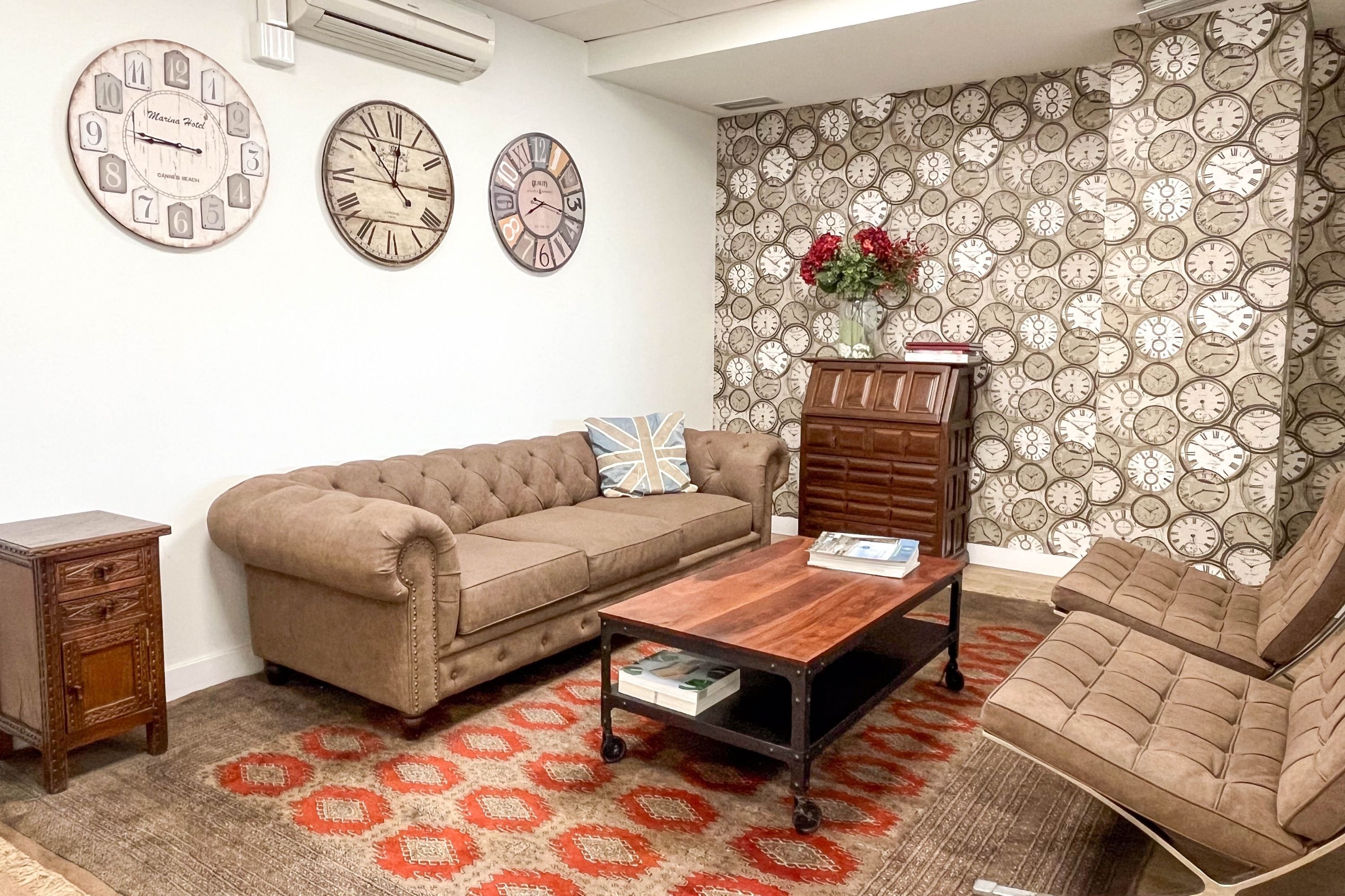 a living room with a couch and clocks on the wall