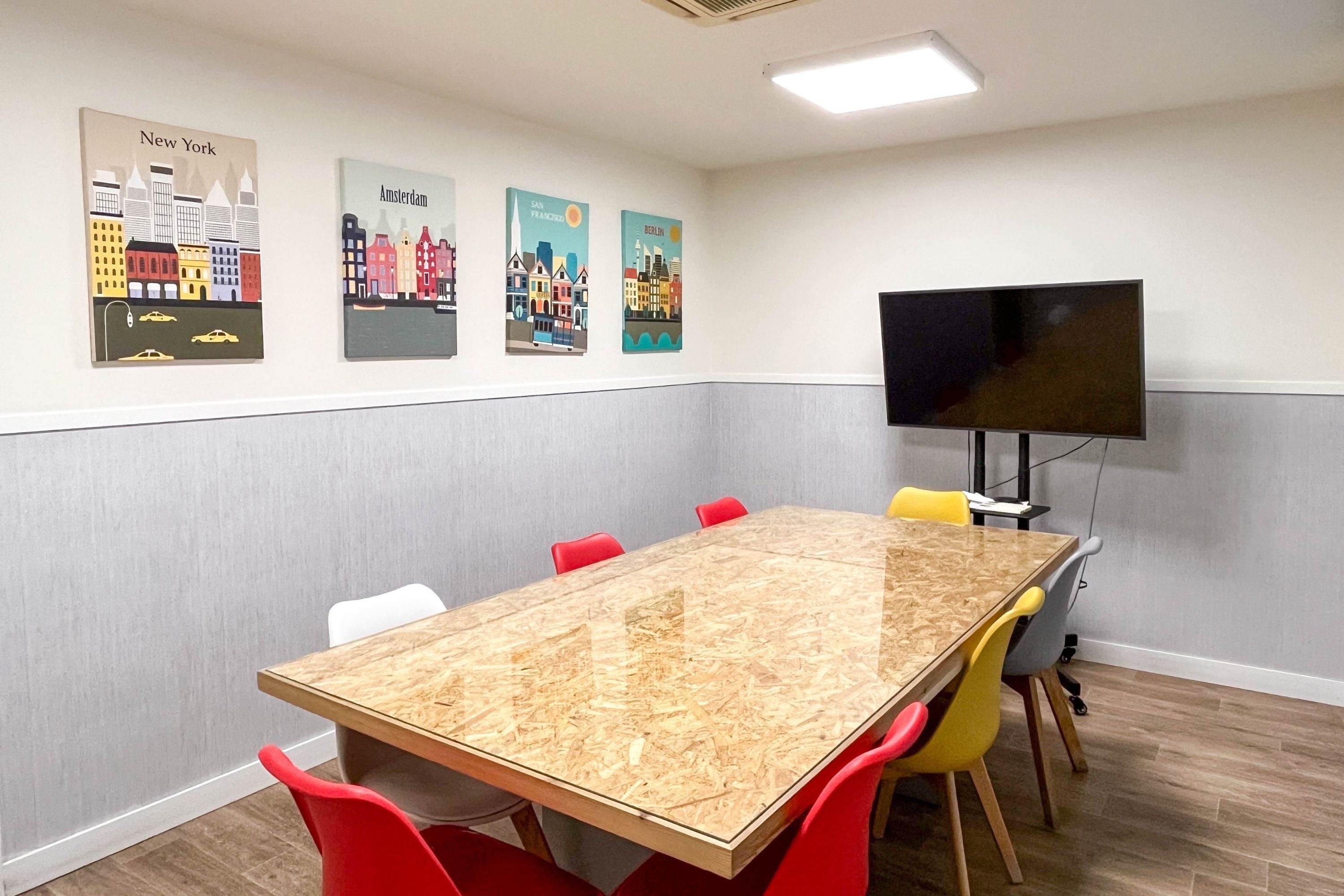 a conference room with a table and chairs and posters of new york and amsterdam