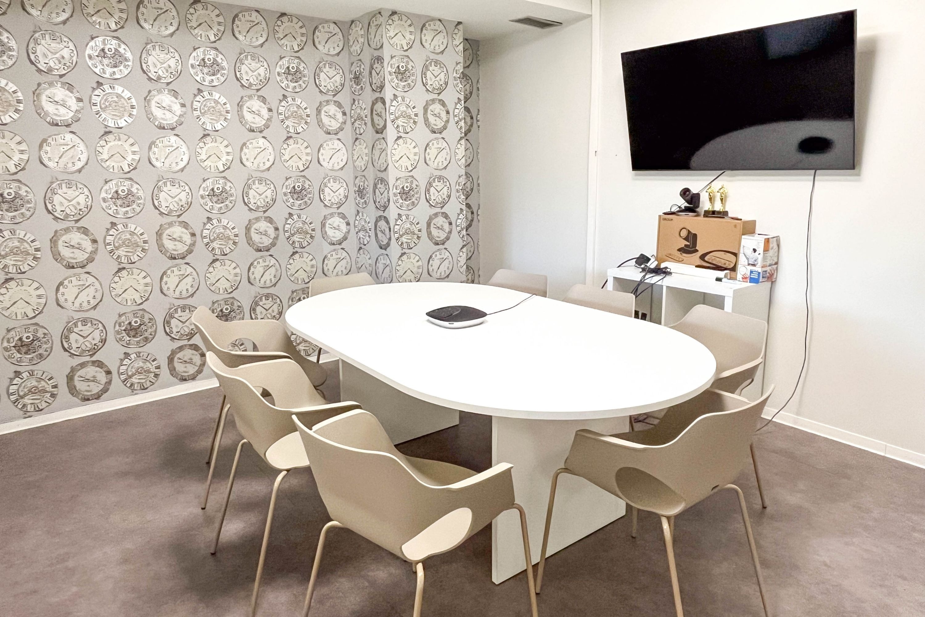 a conference room with a table and chairs and clocks on the wall