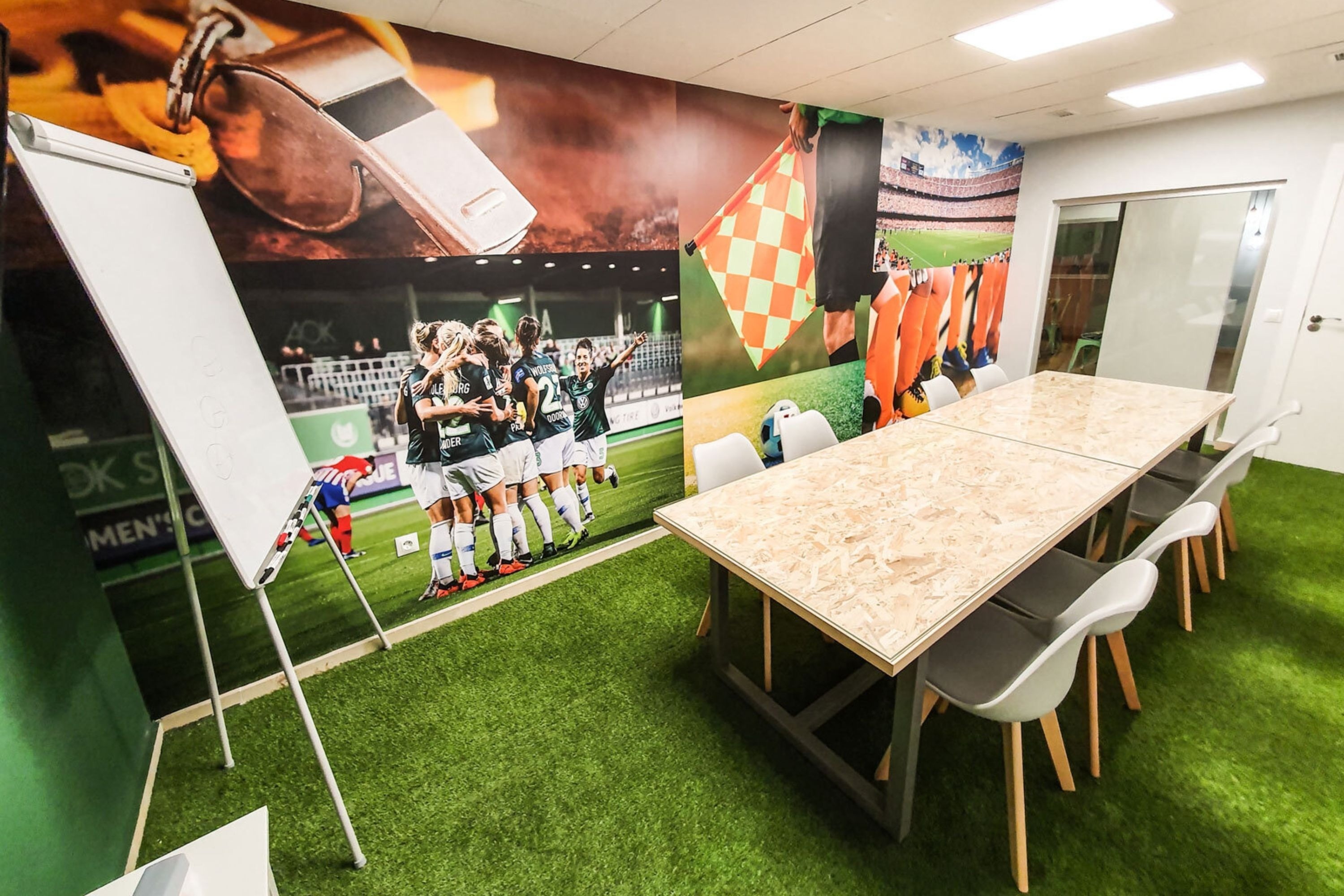 a conference room with a table and chairs and a mural of soccer players on the wall