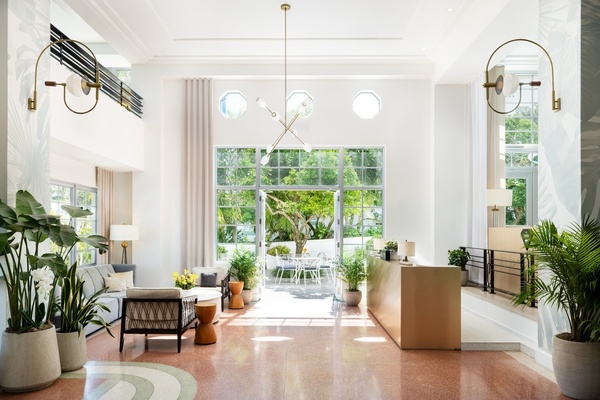 Um hall de entrada espaçoso e luminoso, com design elegante, plantas exuberantes e uma vista convidativa para um jardim exterior.