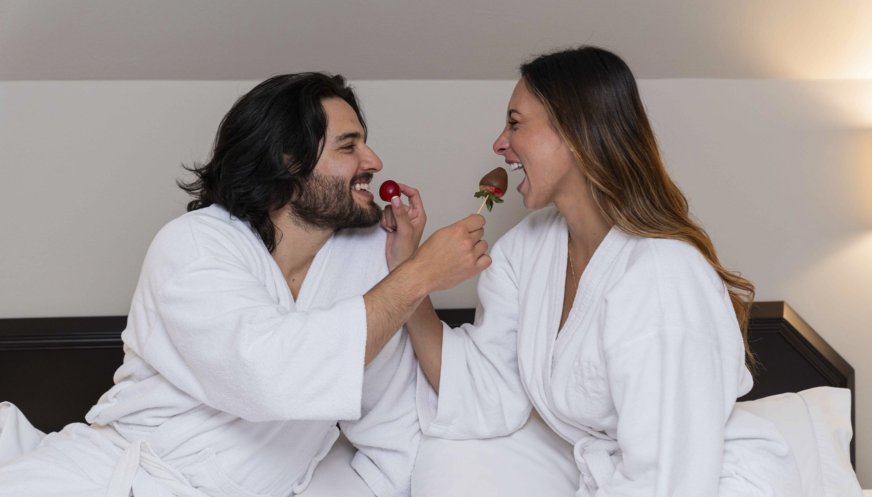 a man is feeding a woman a chocolate covered strawberry