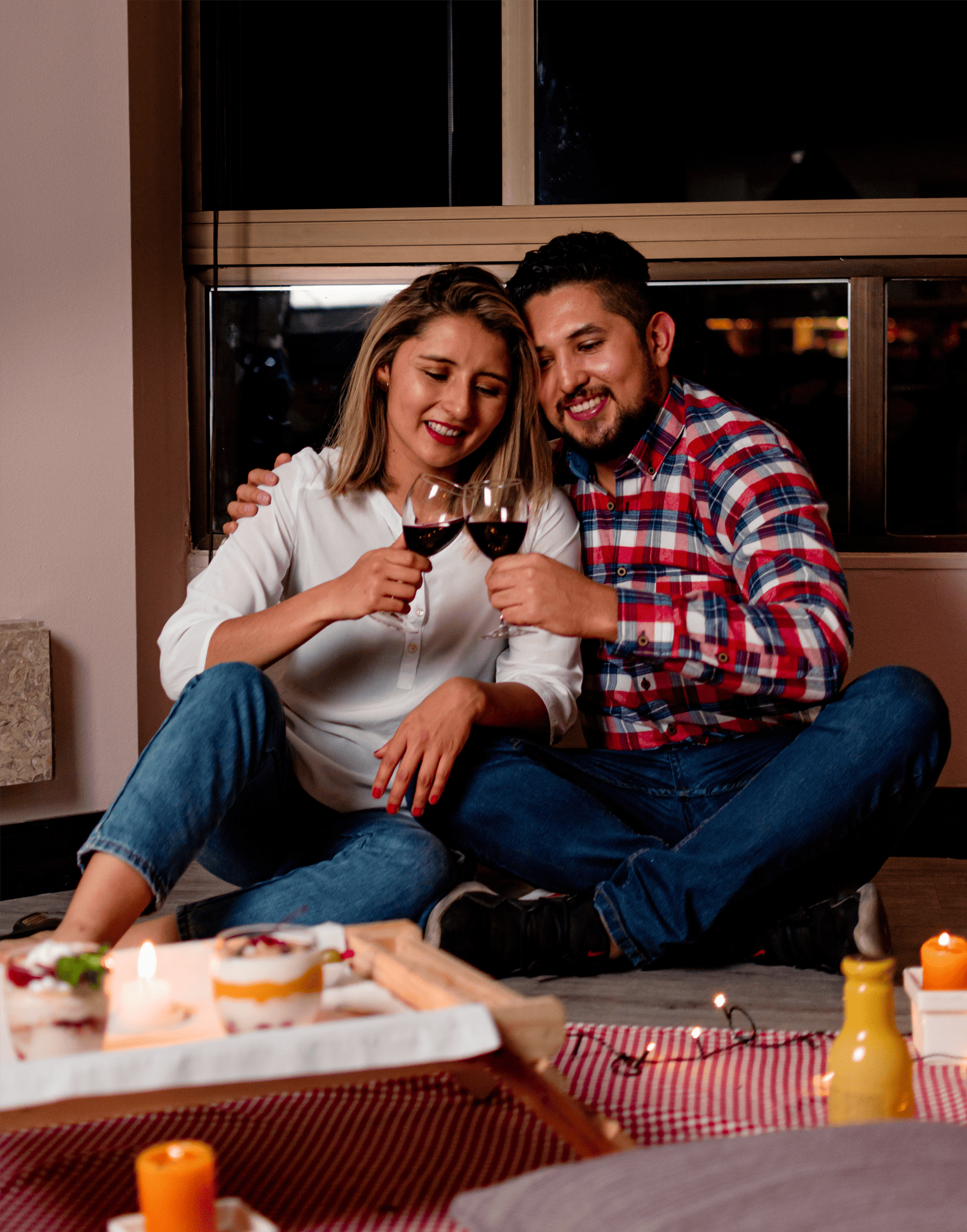 a man and a woman are sitting on the floor drinking wine