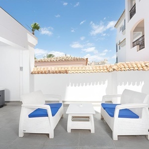 un patio con muebles blancos y azules y una mesa blanca
