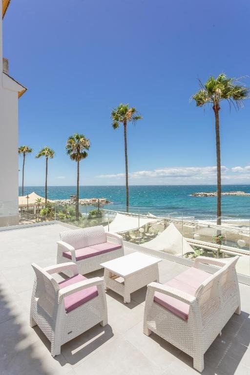 una terraza con muebles blancos y cojines morados con vistas al océano