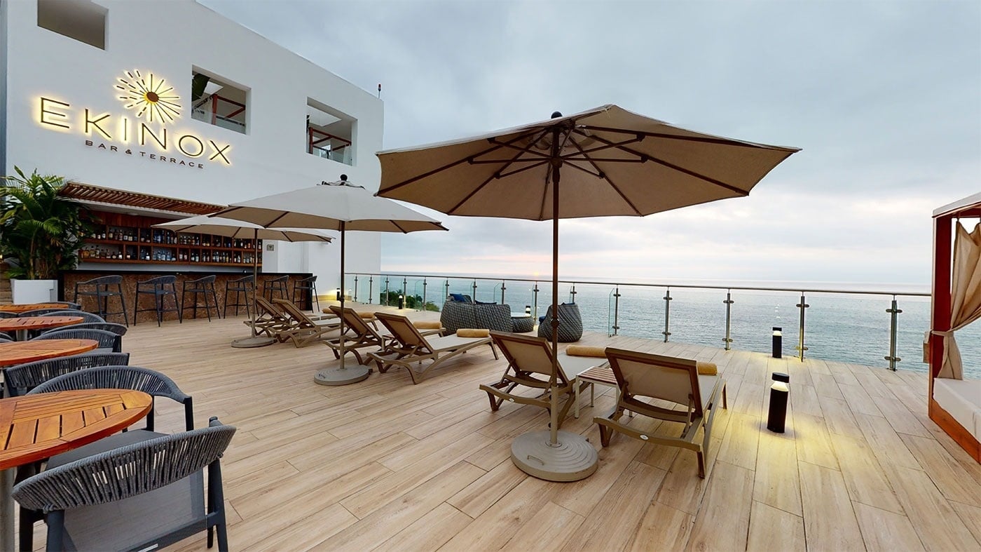 Terraza de hotel con vista al mar, sillas de playa y bar en Hotel Grand Park Royal Puerto Vallarta.