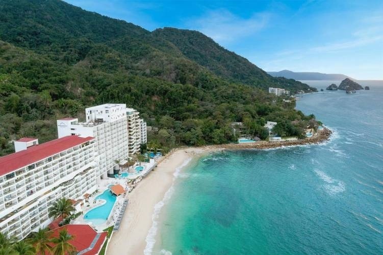 an aerial view of a beach resort with mountains in the background