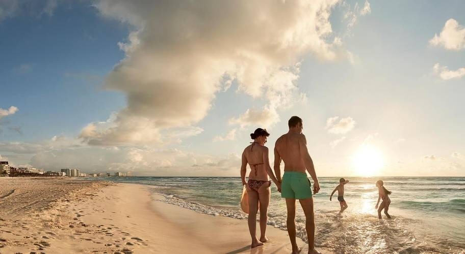 Casal dançando na praia e crianças brincando na água no Park Royal Beach Cancun, Caribe mexicano