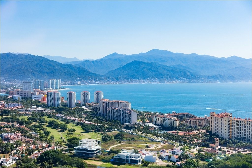 uma vista aérea de uma cidade ao lado do oceano com montanhas ao fundo