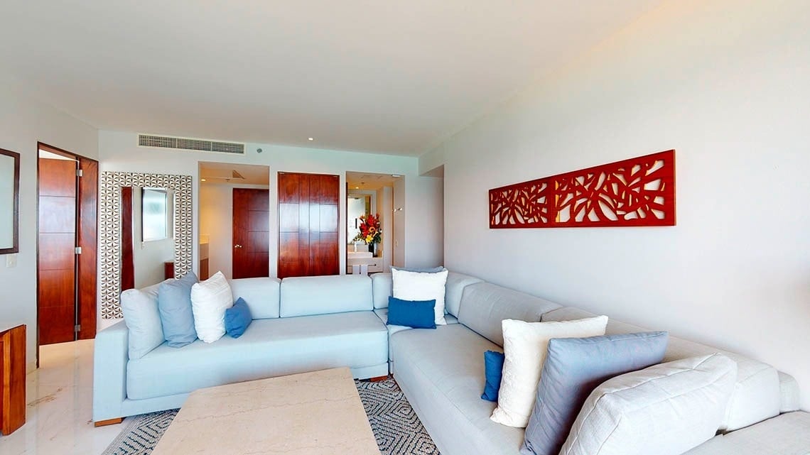 Sala de estar com sofás e mesa em um quarto do Park Royal Beach Cancun Hotel
