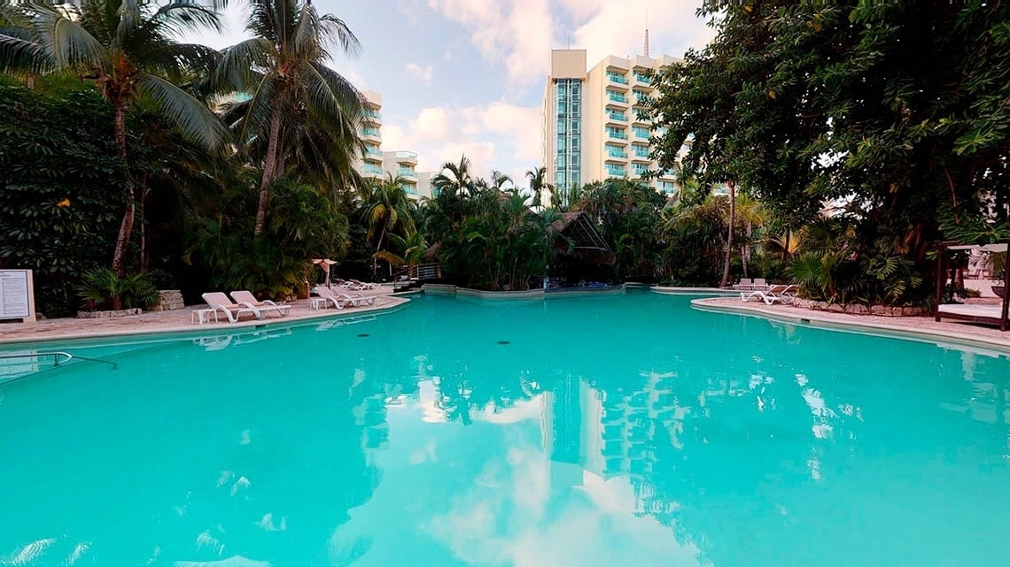 Outdoor swimming pool surrounded by vegetation of the Hotel Grand Park Royal Cozumel