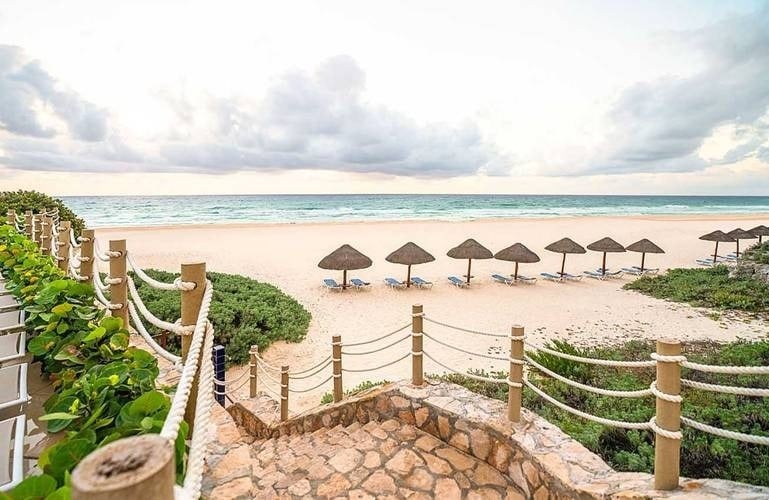 Escalera de piedras hacia la playa, hamacas y sombrillas del Hotel Grand Park Royal Cancún
