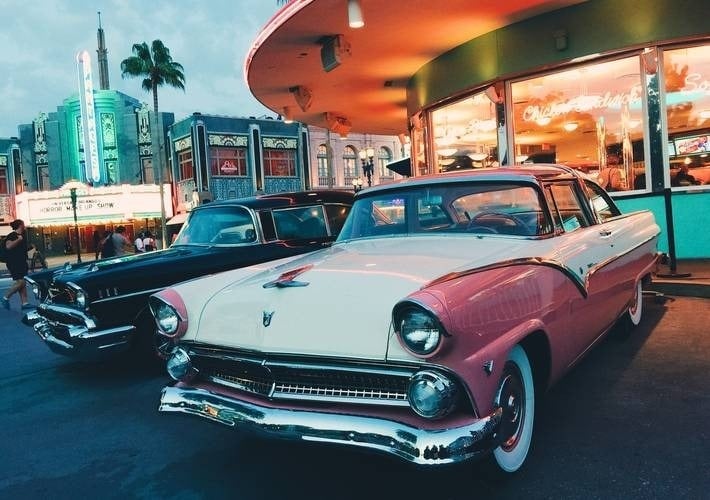 dos autos antiguos están estacionados frente a un restaurante