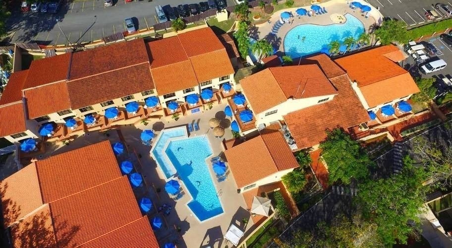 una vista aérea de un complejo de apartamentos con piscinas y sombrillas .