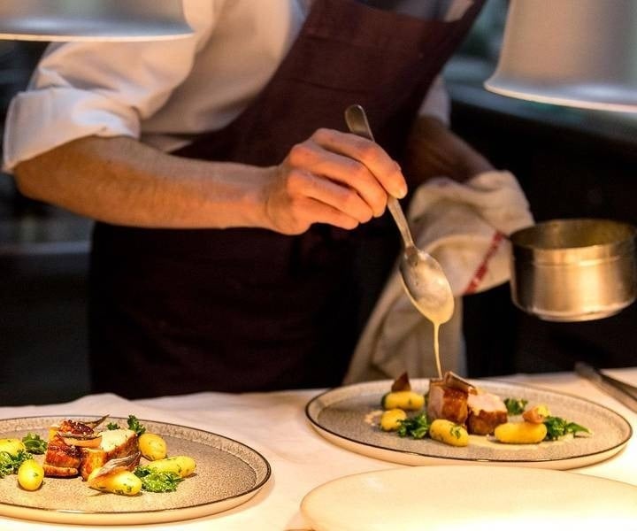 Chef decorando um prato com carne e legumes no Park Royal Beach Cancun Hotel