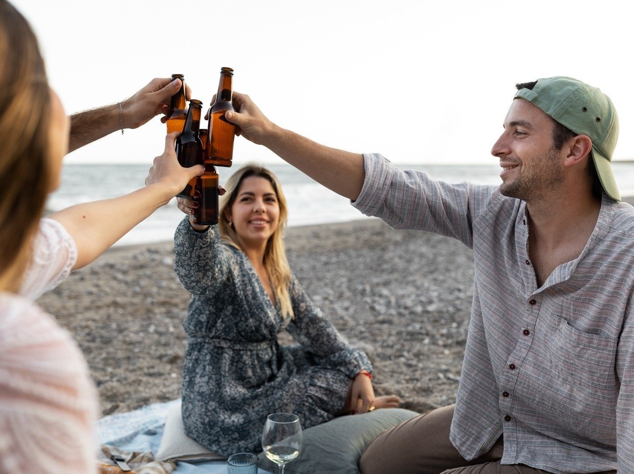 a group of people toasting with beer bottles on the beach