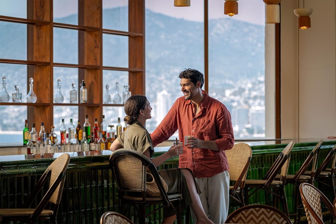 Pareja brindando en el bar del Hotel Park Royal Beach Acapulco, vistas al Pacífico Mexicano. ¡Reserva ya!