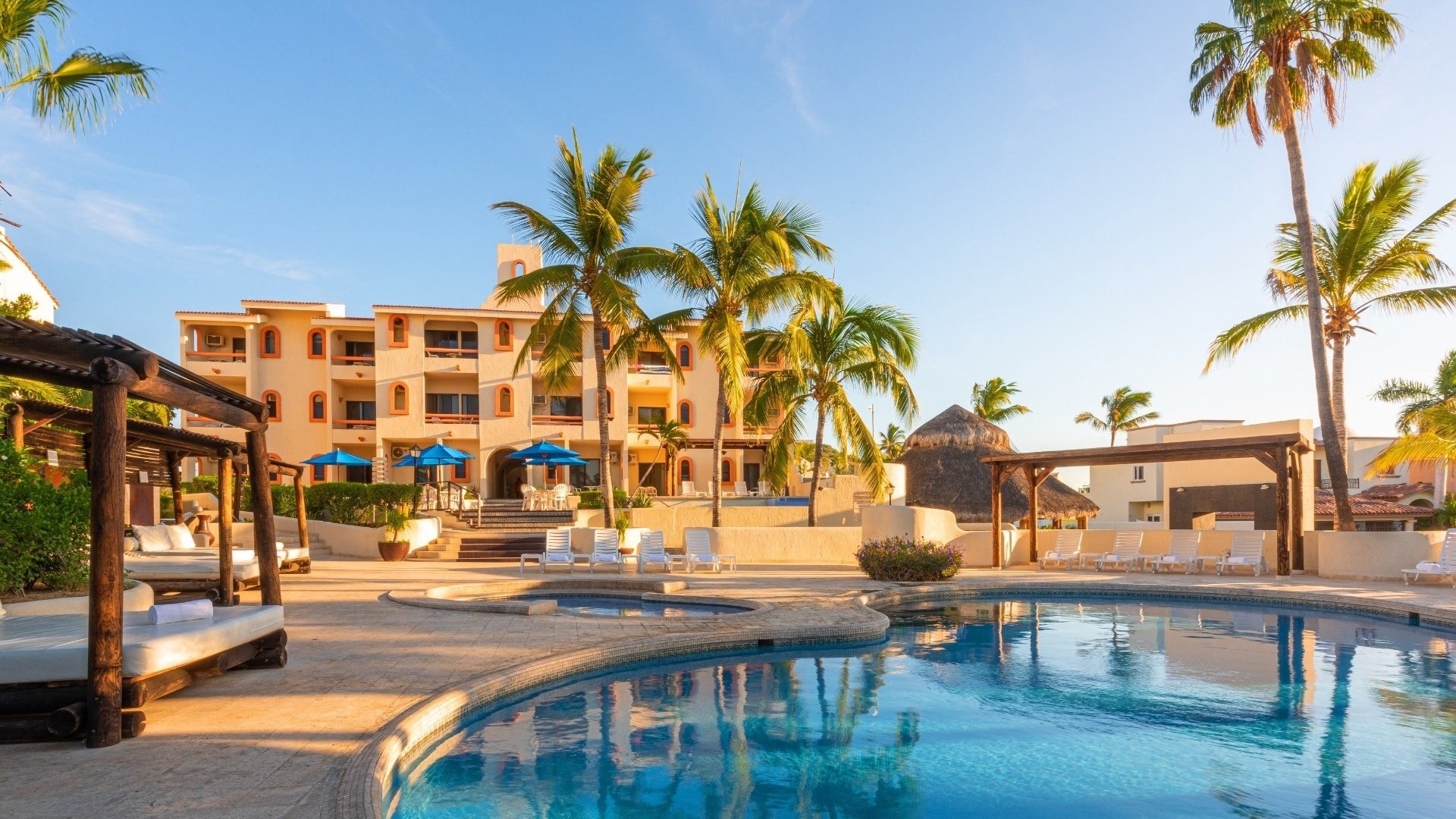 a large swimming pool in front of a building with palm trees