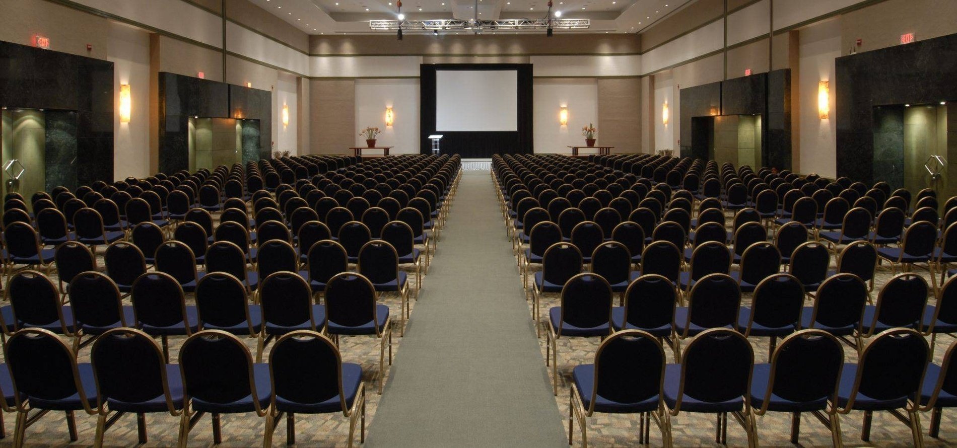 Vista geral da sala de eventos com cadeiras, púlpito e projetor nos hotéis e resorts Park Royal
