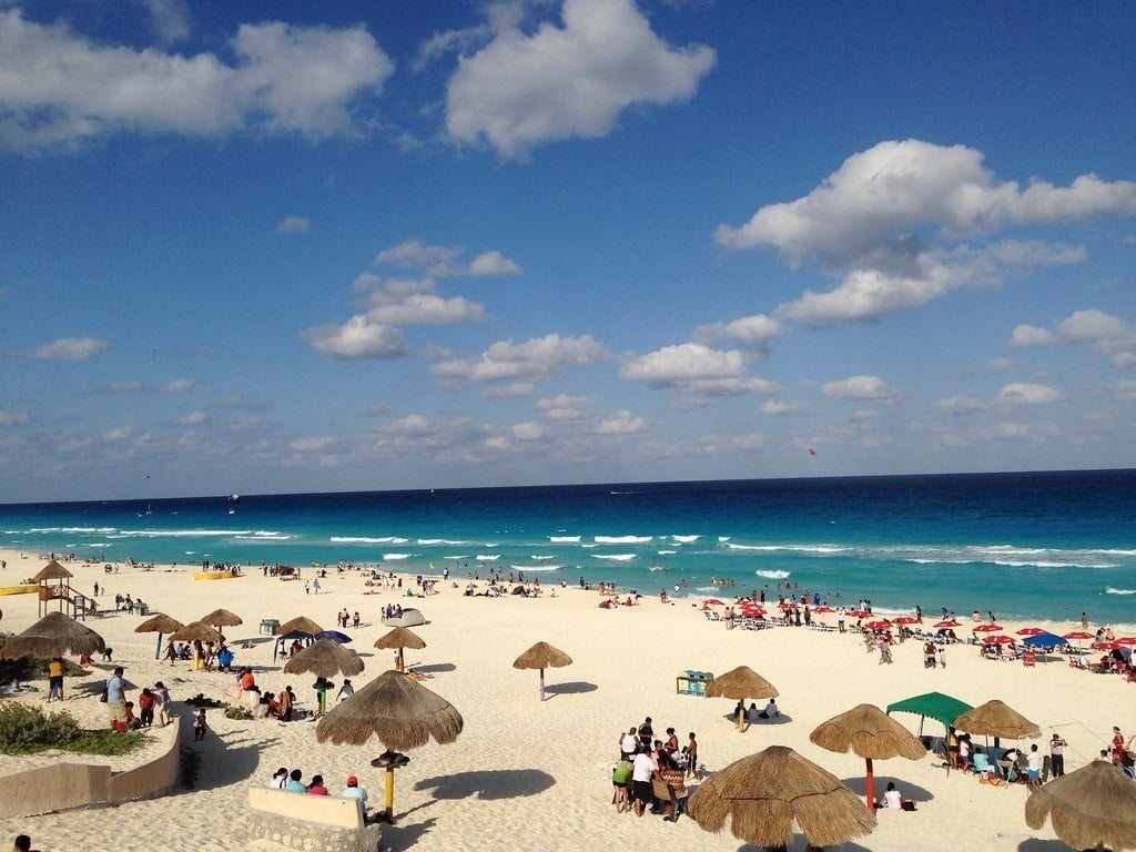 una playa llena de gente y sombrillas en un día soleado