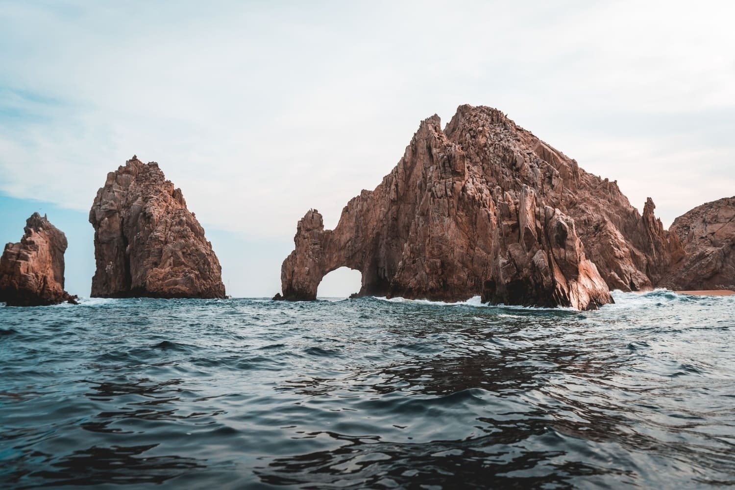 uma grande rocha com um arco no meio do oceano