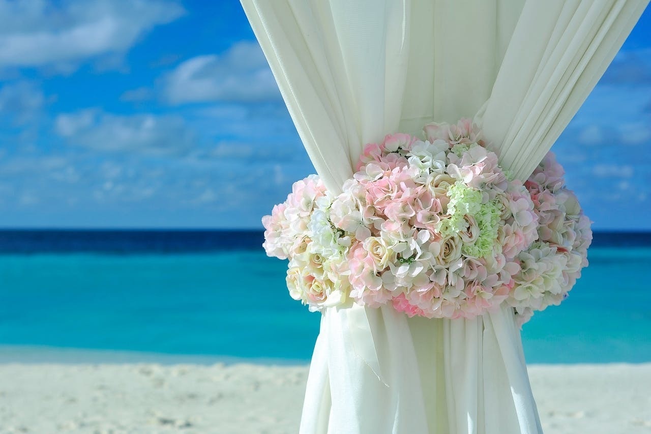 una cortina blanca está decorada con flores rosadas y blancas