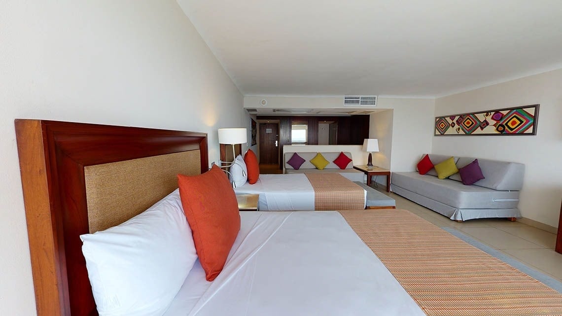 Quarto com todo tipo de conforto: camas e sofás no Hotel Grand Park Royal Puerto Vallarta