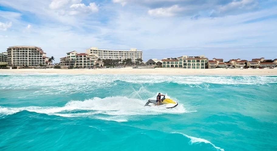 Hombre en moto acuática en frente del Hotel Grand Park Royal Cancún en el Caribe mexicano