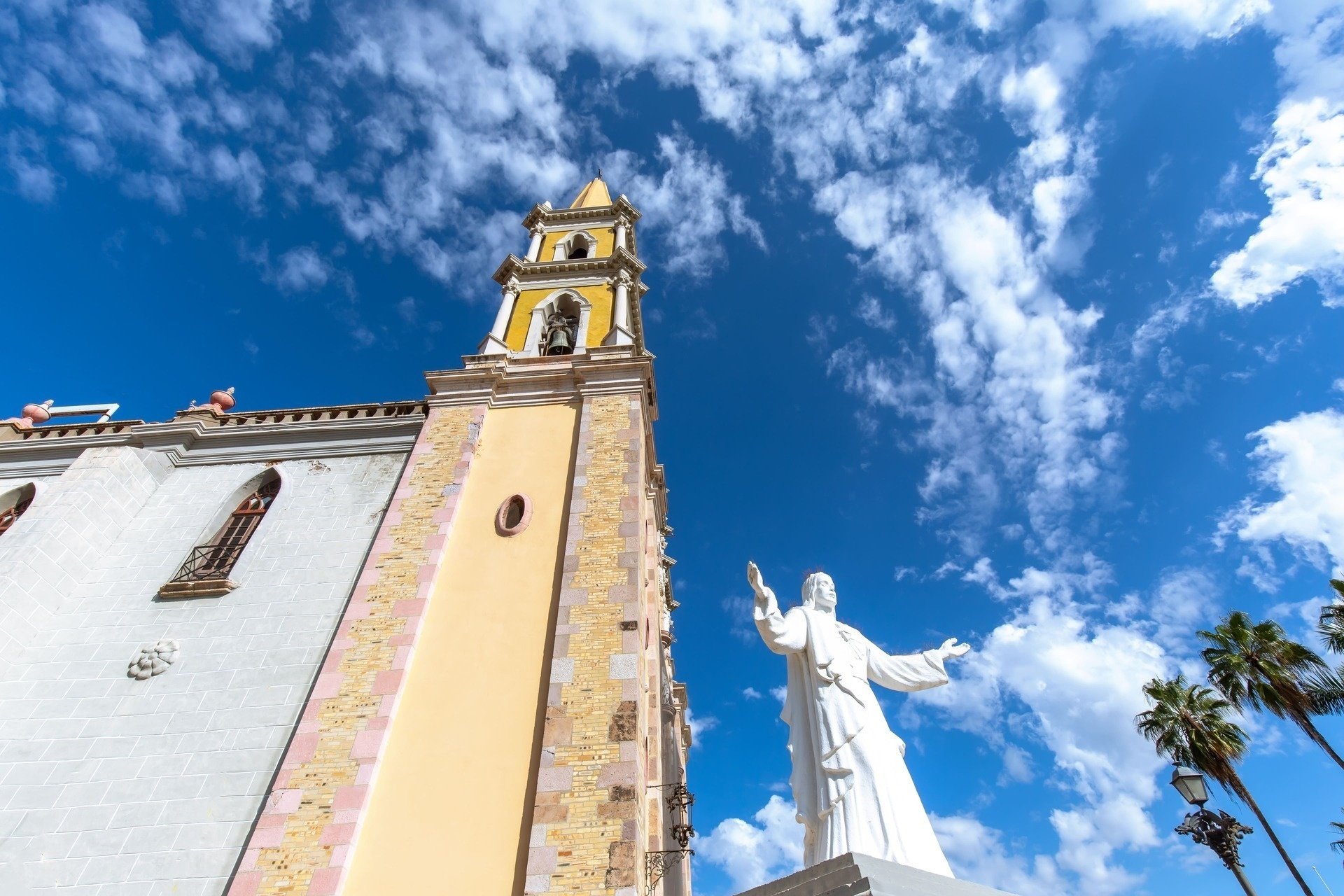 a church with a bell tower and a statue of jesus in front of it