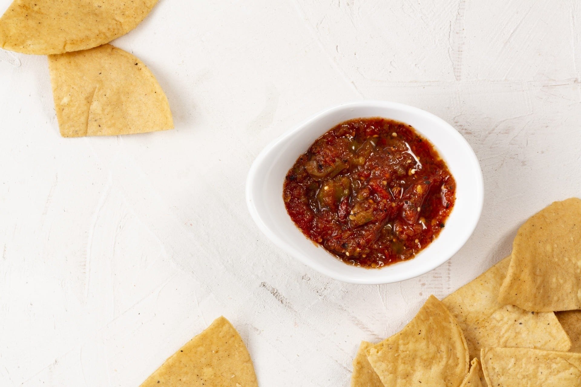 uma tigela de molho ao lado de chips de milho