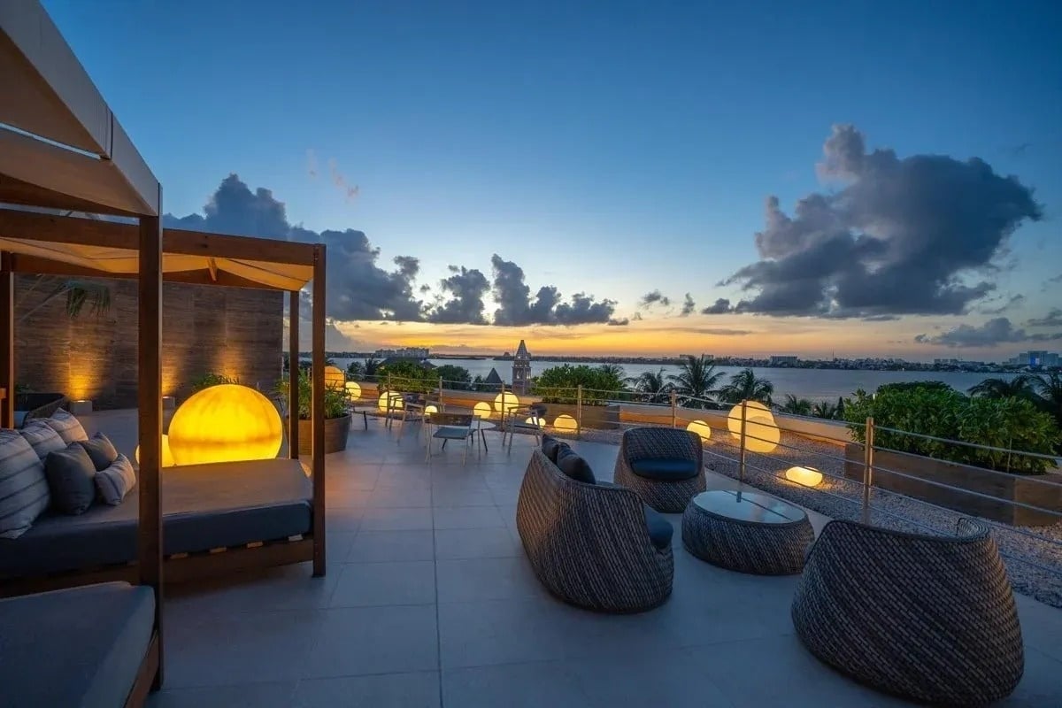 uma varanda com cadeiras e mesas ao pôr do sol com vista para o oceano