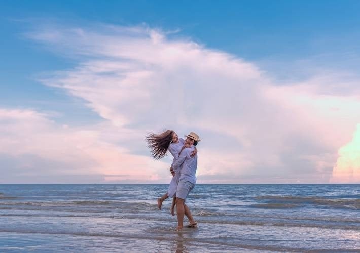 a man is holding a woman in his arms on the beach .