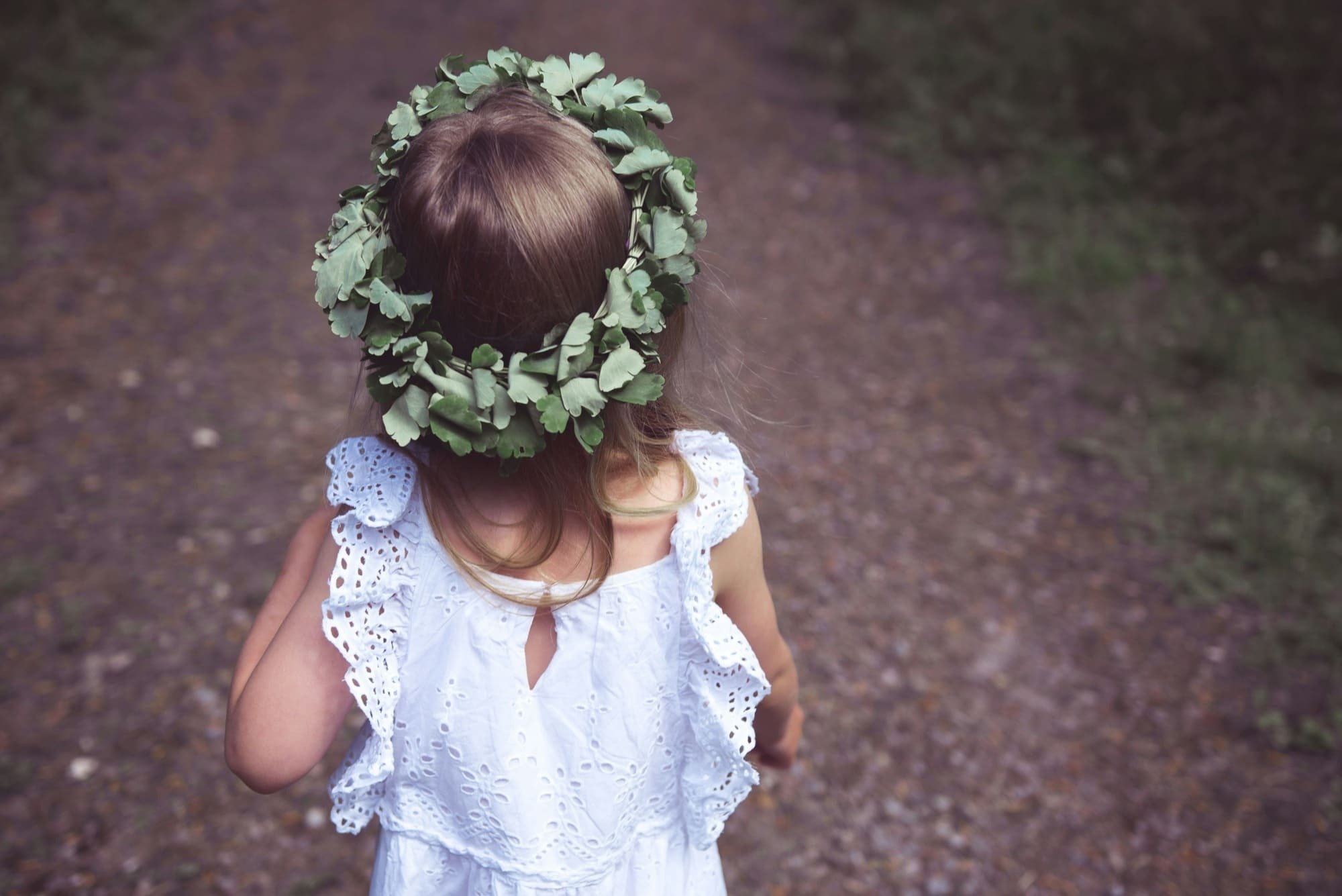 a little girl wearing a wreath of leaves on her head