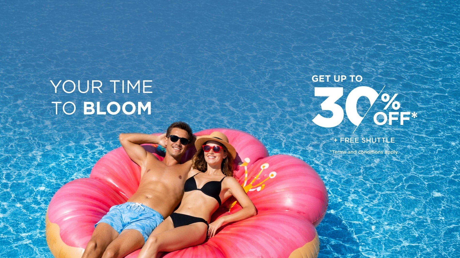 A smiling couple relaxes on a pink flower-shaped inflatable in a swimming pool, alongside text promoting a "GET UP TO 30% OFF* + FREE SHUTTLE" offer and the phrase "YOUR TIME TO BLOOM."